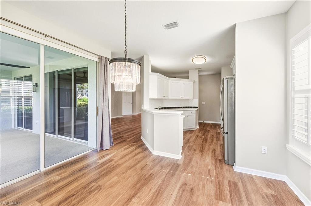 7005 Pinnacle Lane, Unit 1501 Naples, FL 34110 - Photo 17 of 46 a kitchen with white cabinets and wooden floor