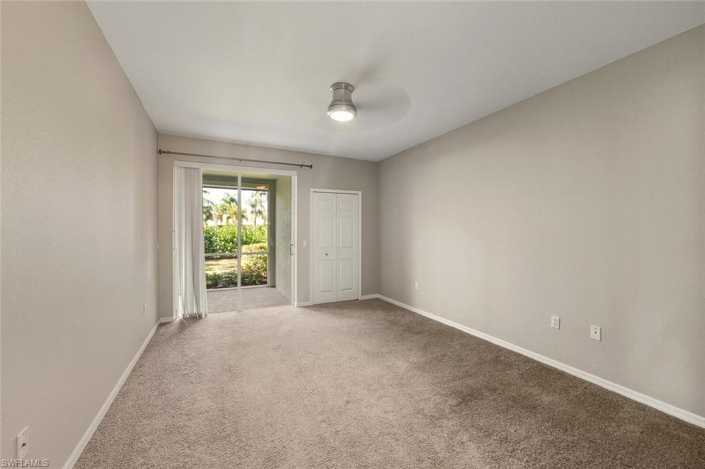 7005 Pinnacle Lane, Unit 1501 Naples, FL 34110 - Photo 18 of 46 an empty room with windows and a ceiling fan