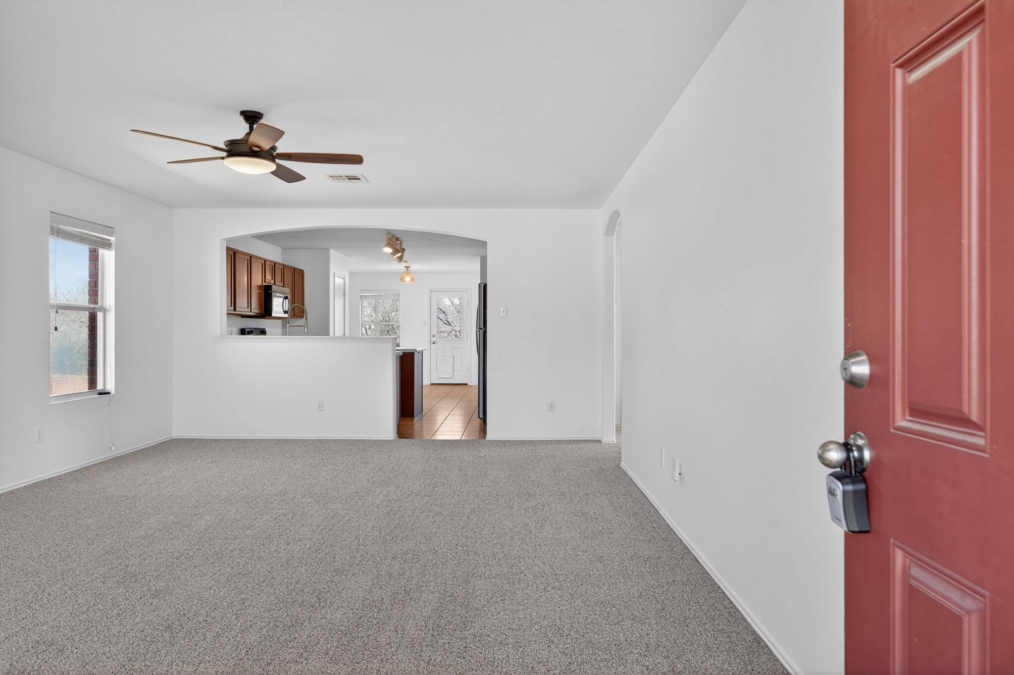 13629 Coomer Path Pflugerville, TX 78660 - Photo 3 of 30 Unfurnished living room with arched walkways, a ceiling fan, and light colored carpet
