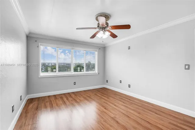 a view of empty room with wooden floor and fan