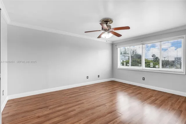 a view of empty room with wooden floor and fan