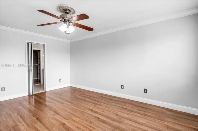 an empty room with wooden floor and ceiling fan