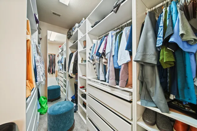 a view of walk in closet with clothes and shoes