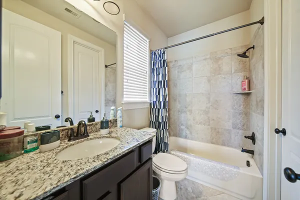 a bathroom with a granite countertop sink toilet mirror and bathtub