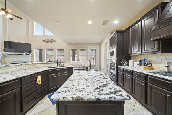 a large kitchen with kitchen island granite countertop a stove top oven a sink dishwasher a dining table and chairs with wooden floor