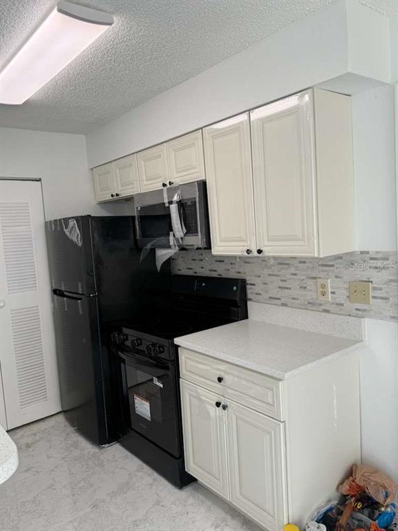1089 South Hiawassee Road, Unit 314 Orlando, FL 32835 - Photo 16 of 24 a kitchen with a refrigerator and white cabinets