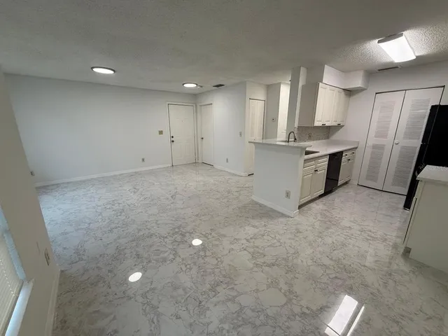 a view of a kitchen with refrigerator and white cabinets