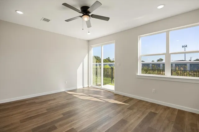 a view of an empty room with a window and wooden floor