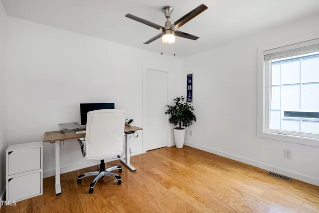an empty room with wooden floor fan and windows