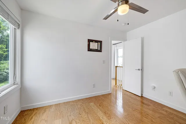 a view of a hallway with wooden floor and a living room