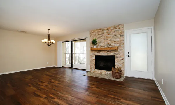 an empty room with wooden floor fireplace and windows