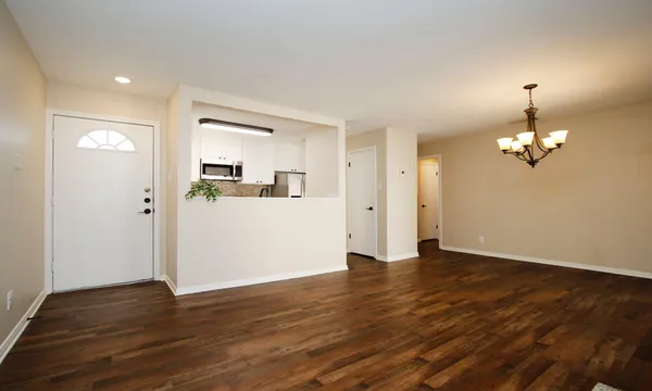 a view of empty room with wooden floor and kitchen view