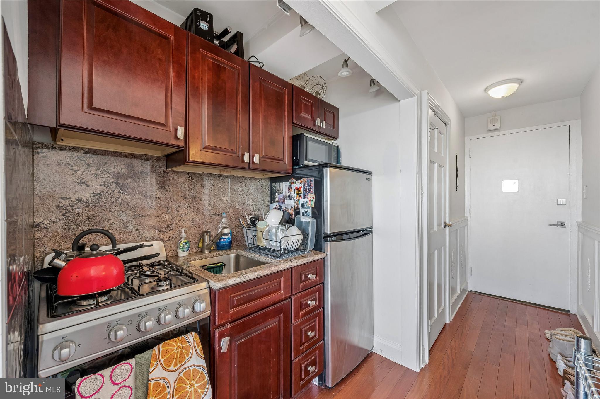 1810 Rittenhouse Square, Unit 2007 Philadelphia, PA 19103 - Photo 12 of 25 a kitchen with stainless steel appliances granite countertop a stove a refrigerator and a wooden cabinets