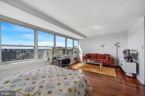 a bedroom with a bed and large windows