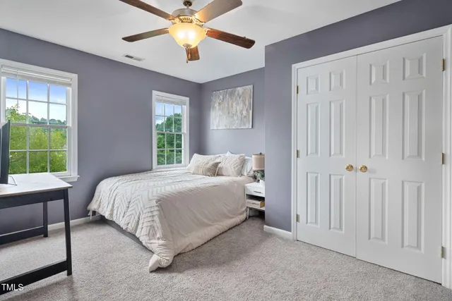 a bedroom with a large bed and a chandelier fan