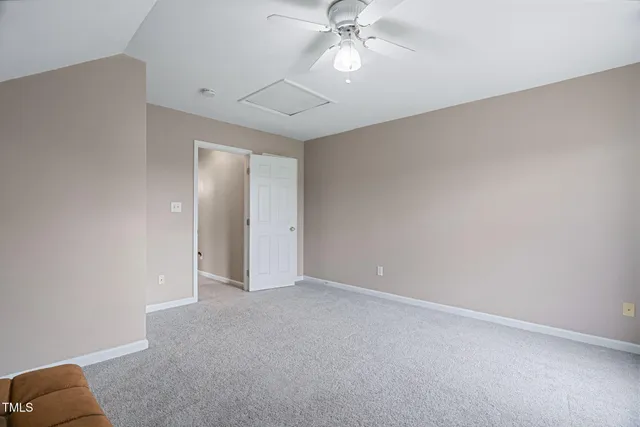 an empty room with a chandelier fan and closet