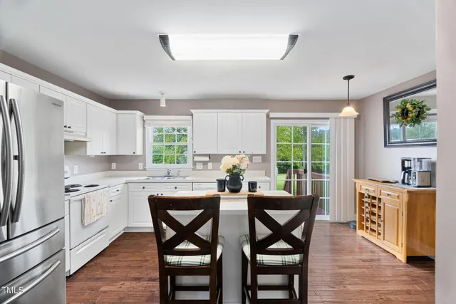 a kitchen with stainless steel appliances granite countertop wooden floor and white cabinets