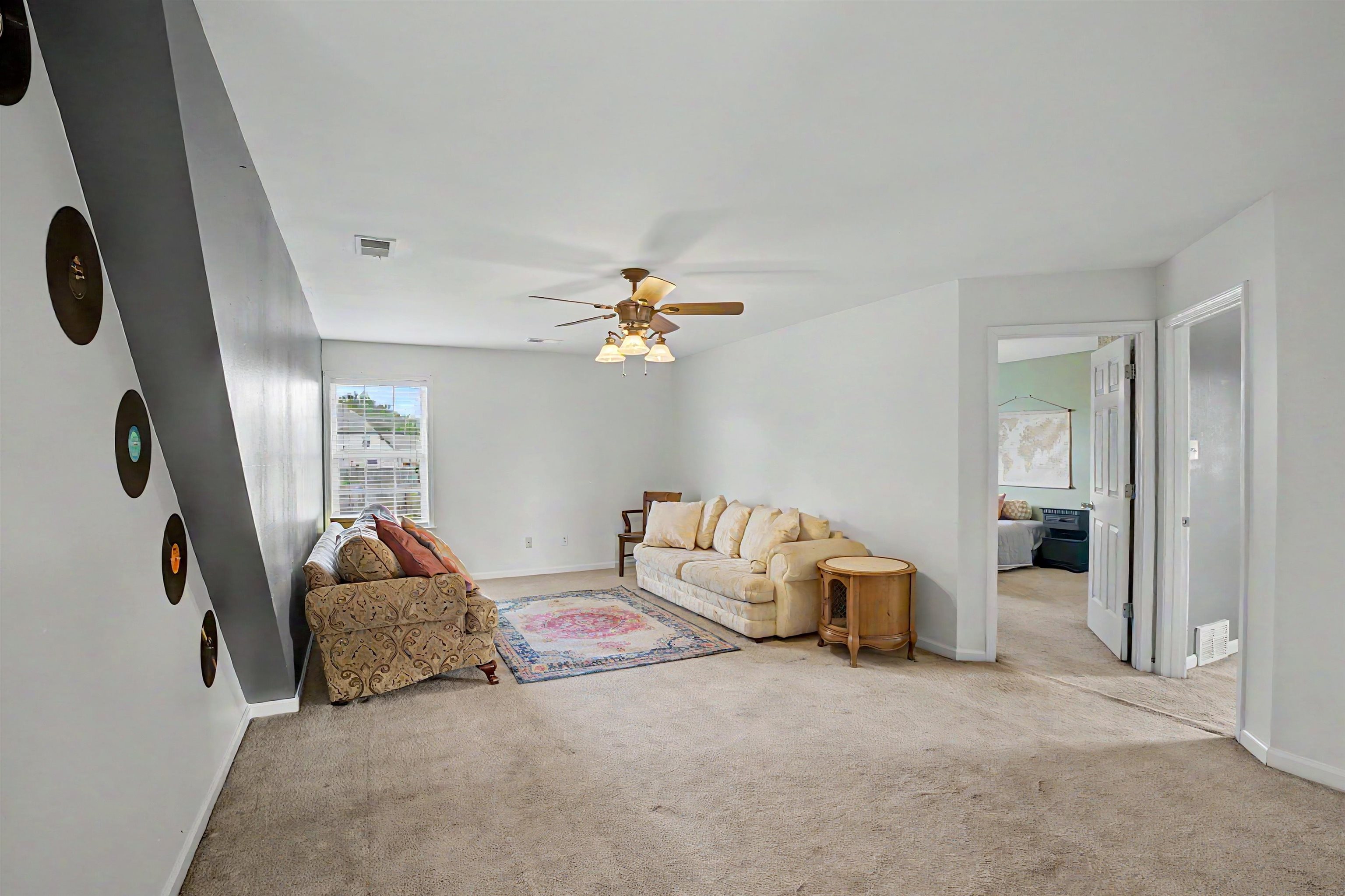 134 Rembert Drive Atoka, TN 38004 - Photo 32 of 38 Spacious carpeted living area featuring a ceiling fan with integrated lighting, a window providing natural light, and a white paneled door