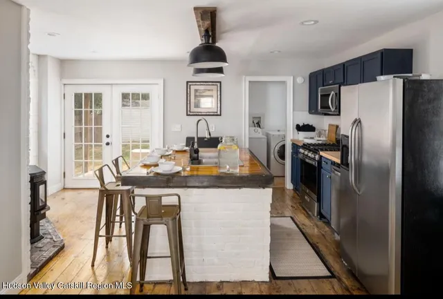 a kitchen with stainless steel appliances granite countertop a refrigerator a stove a sink a dining table and chairs with wooden floor