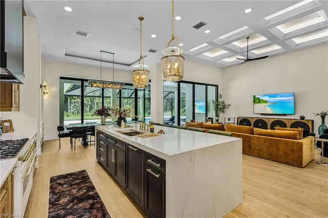 a large kitchen with stainless steel appliances a stove a sink dishwasher and a dining table with the living room view