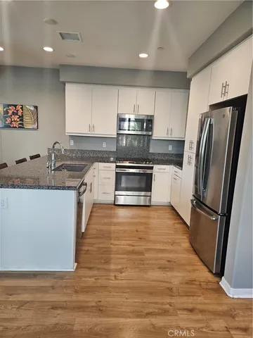 a kitchen with stainless steel appliances granite countertop a refrigerator a stove a sink and a microwave