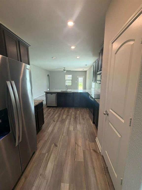 310 Foster Lane Anna, TX 75409 - Photo 3 of 15 Open-concept kitchen featuring wood-finish flooring, dark wood cabinetry, stainless steel appliances, and recessed lighting