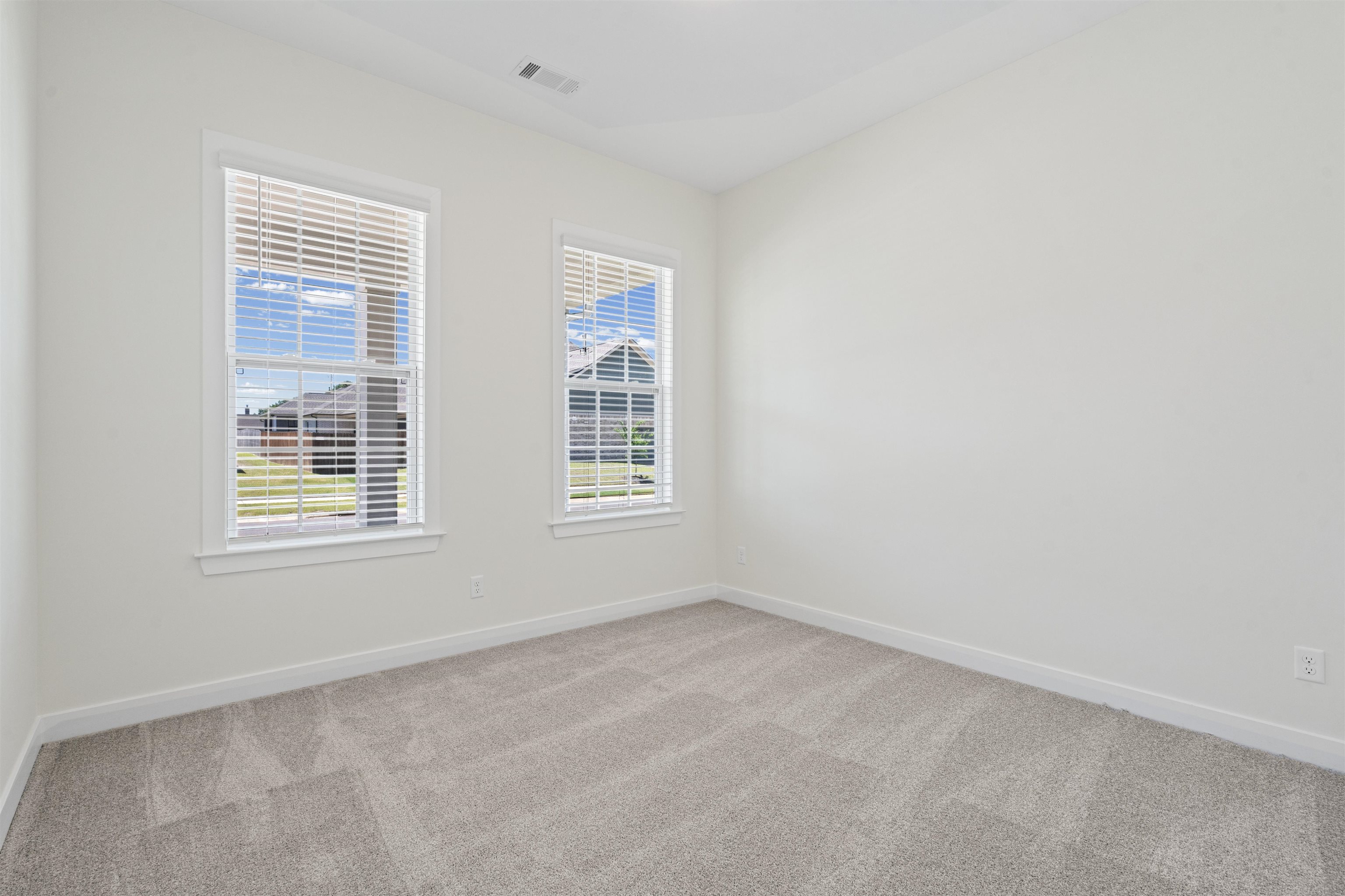 5666 Pleasant Pk Place Arlington, TN 38002 - Photo 5 of 27 Bright interior room featuring two windows with white blinds, neutral wall paint, and gray patterned carpeting