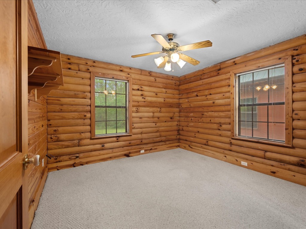 12868 Levi Road Willis, TX 77378 - Photo 16 of 41 Comfortable secondary bedroom with warm wood walls, soft natural light, and a cozy, inviting feel.