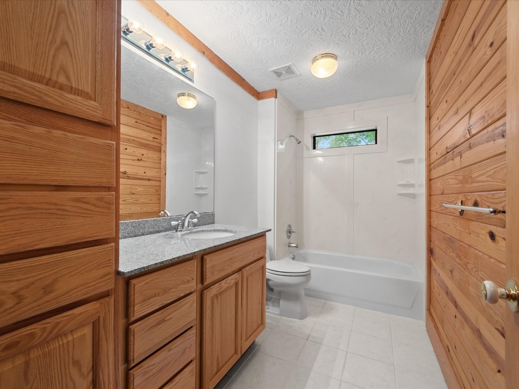 12868 Levi Road Willis, TX 77378 - Photo 17 of 41 Clean and bright secondary bathroom featuring granite countertops, warm wood cabinetry, and a full tub/shower combo.