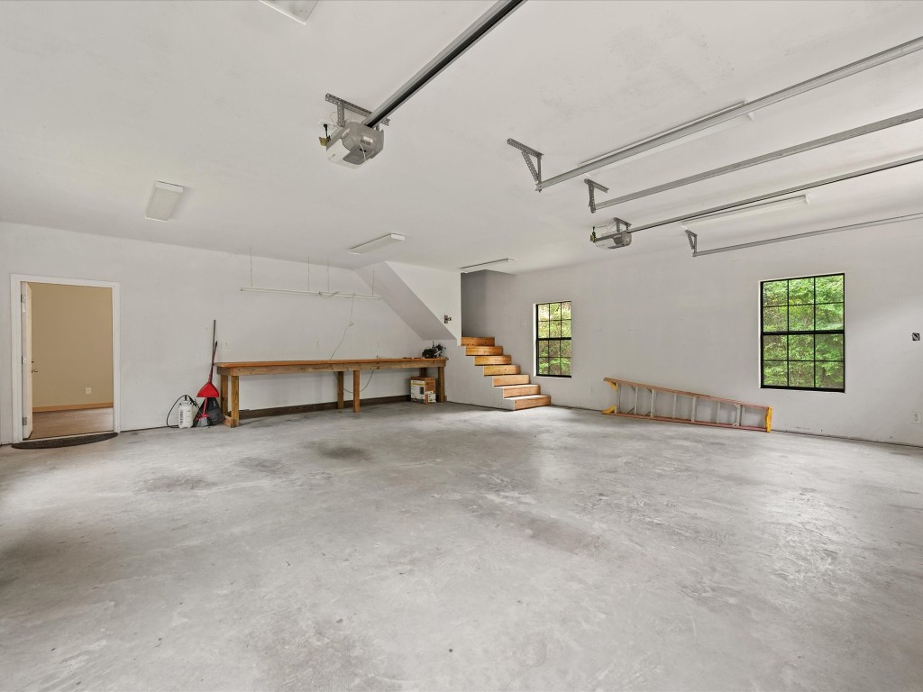 12868 Levi Road Willis, TX 77378 - Photo 22 of 41 Spacious interior garage with workshop area, ample storage, and stair access to upstairs space.