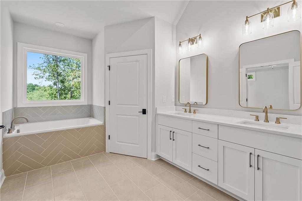 5715 Broad River View, Unit 449 Peachtree Corners, GA 30092 - Photo 25 of 29 a spacious bathroom with double vanity a mirror a bathtub and a double vanity sink