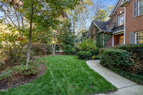 a view of a brick house with a yard and plants