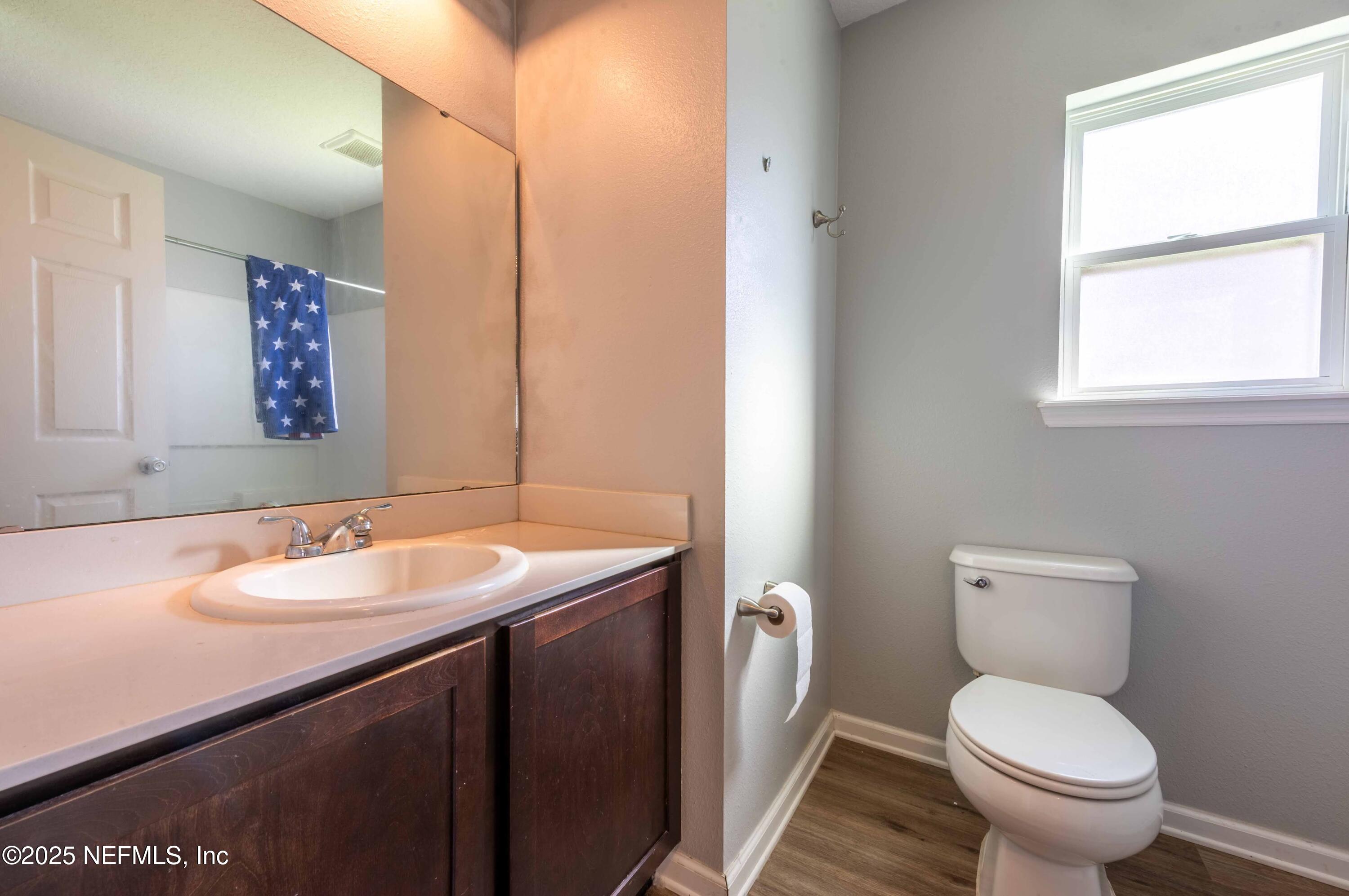 77041 Cobblestone Drive Yulee, FL 32097 - Photo 9 of 23 a bathroom with a granite countertop toilet a sink and a mirror