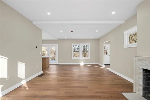a view of an empty room with a window and wooden floor