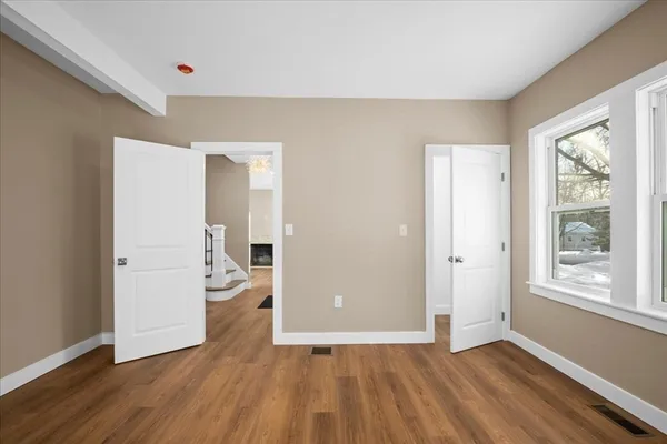 an empty room with wooden floor and windows