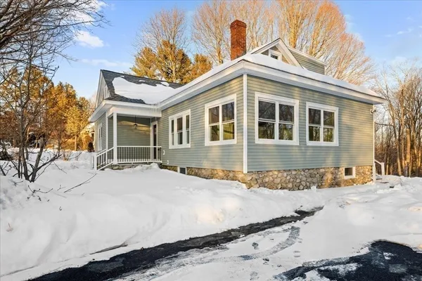 a front view of a house with a yard covered with snow