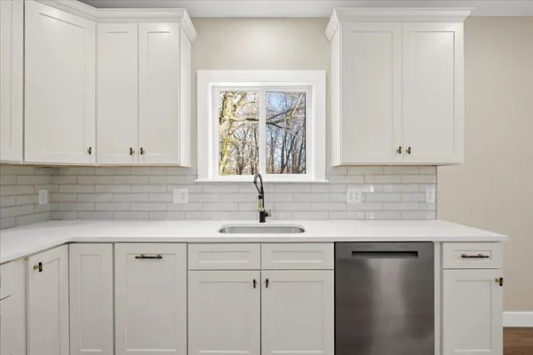 a kitchen with white cabinets and a window