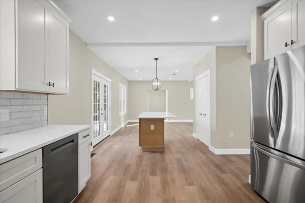 a kitchen with stainless steel appliances granite countertop a refrigerator a sink dishwasher a stove and white countertops with wooden floor