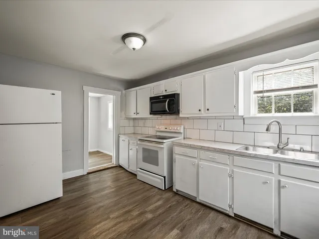 a kitchen with a sink a refrigerator and white cabinets
