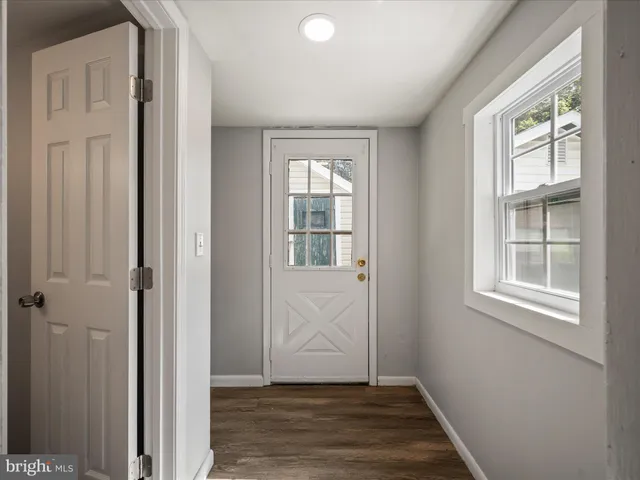 an empty room with wooden floor closet and windows