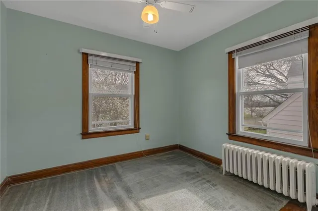 a view of an empty room with window and a ceiling fan
