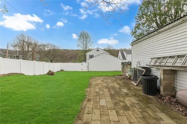 a view of a white house next to a yard with big trees