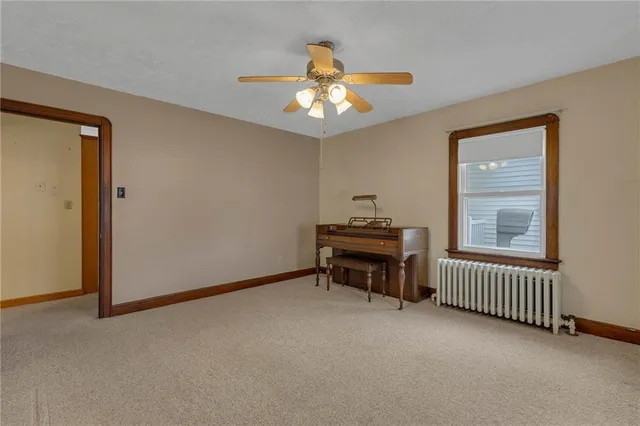 a view of an empty room with window and chandelier fan
