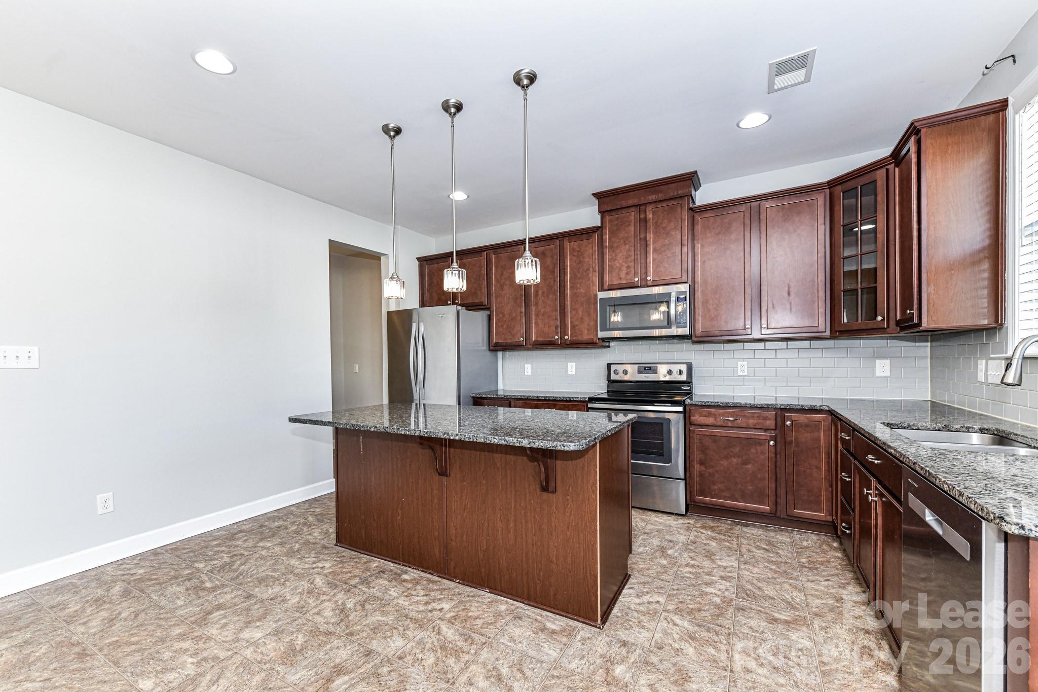 4316 Hubbard Road Charlotte, NC 28269 - Photo 19 of 46 a kitchen with stainless steel appliances granite countertop a stove top oven a sink dishwasher a dining table and chairs with wooden floor