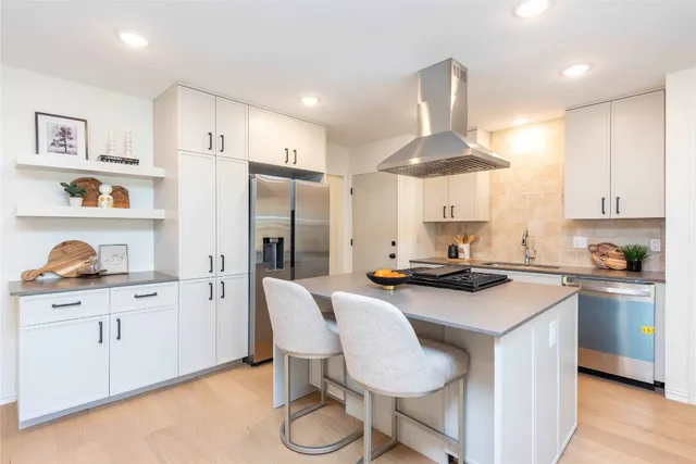 a kitchen with stainless steel appliances a sink a stove a refrigerator and cabinets