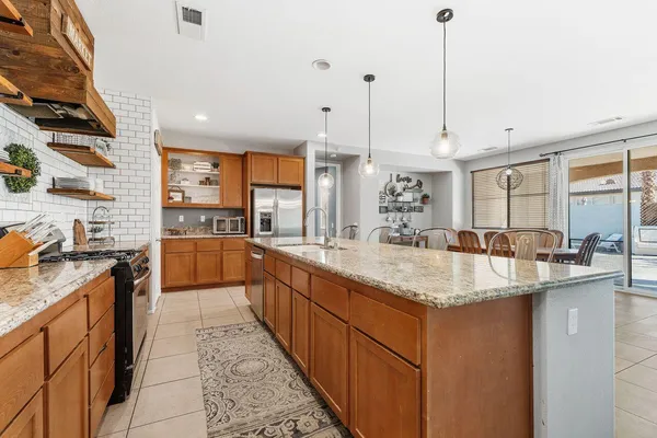 a large kitchen with kitchen island a large counter top a sink a stove and a center island