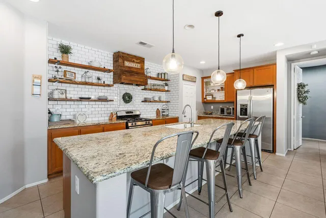 a kitchen with stainless steel appliances granite countertop table chairs and a view of living room
