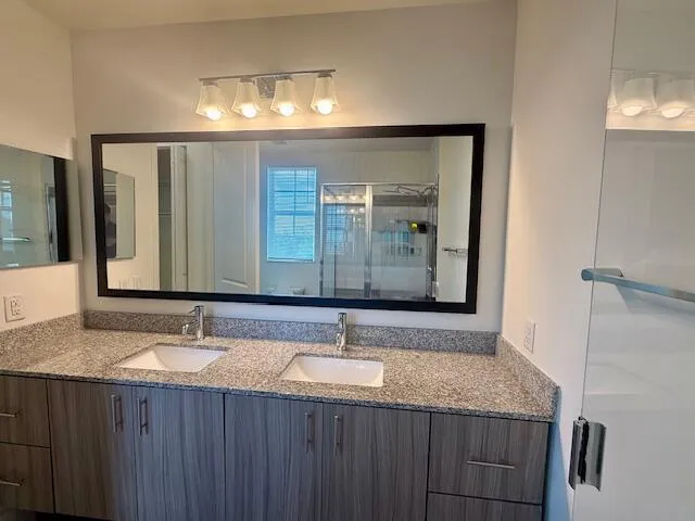 a bathroom with a granite countertop double vanity sink and mirror