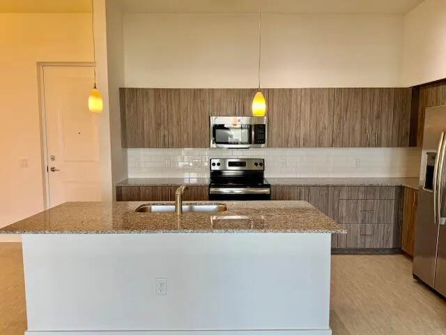 a kitchen with stainless steel appliances granite countertop a sink a stove top oven a refrigerator and a oven