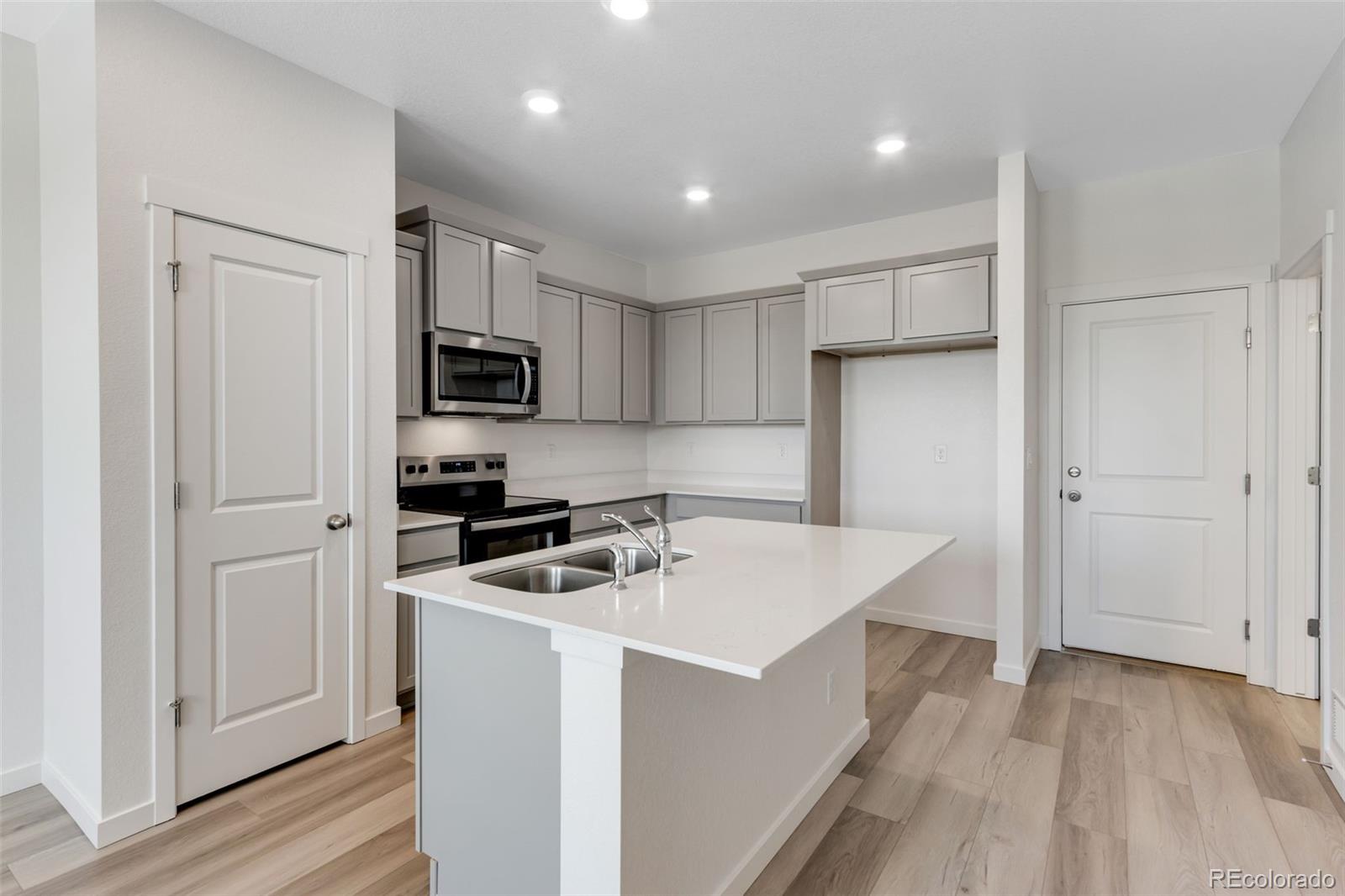 2360 Merlot Street Fort Lupton, CO 80621 - Photo 4 of 21 a kitchen that has a sink a microwave a refrigerator and cabinets